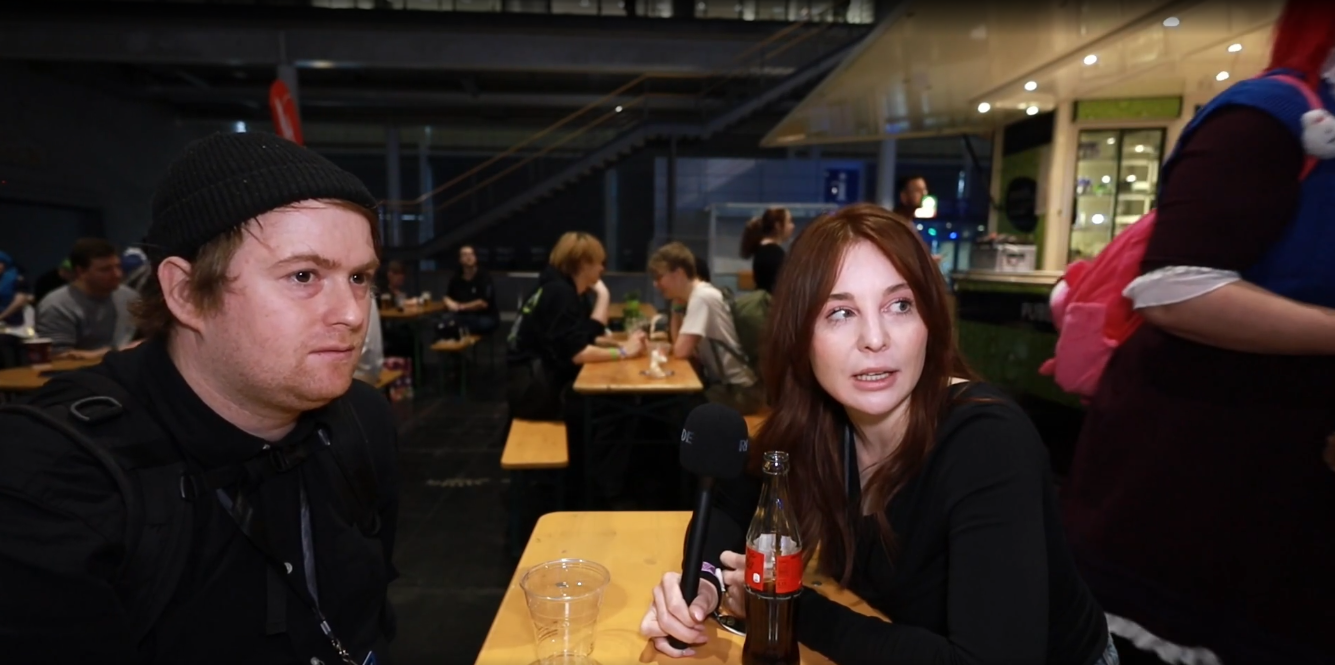 Verena im Gespräch mit einem Besucher am Tisch im Food-Bereich der Gamevasion